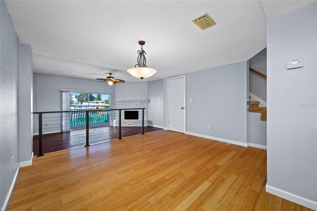 A living room features light wood flooring, a sunken area with a fireplace, and stairs — 12424 CAPRI CIRCLE N UNIT 5, TREASURE ISLAND, FL