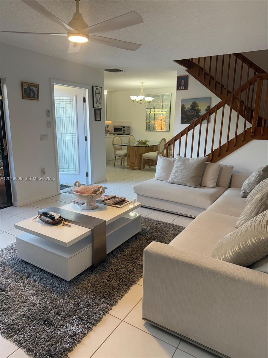 A living room with a white sectional sofa, coffee table, and staircase leads to a dining area — 9101 SW 19th Pl # C, Davie FL 33324, DAVIE, FL