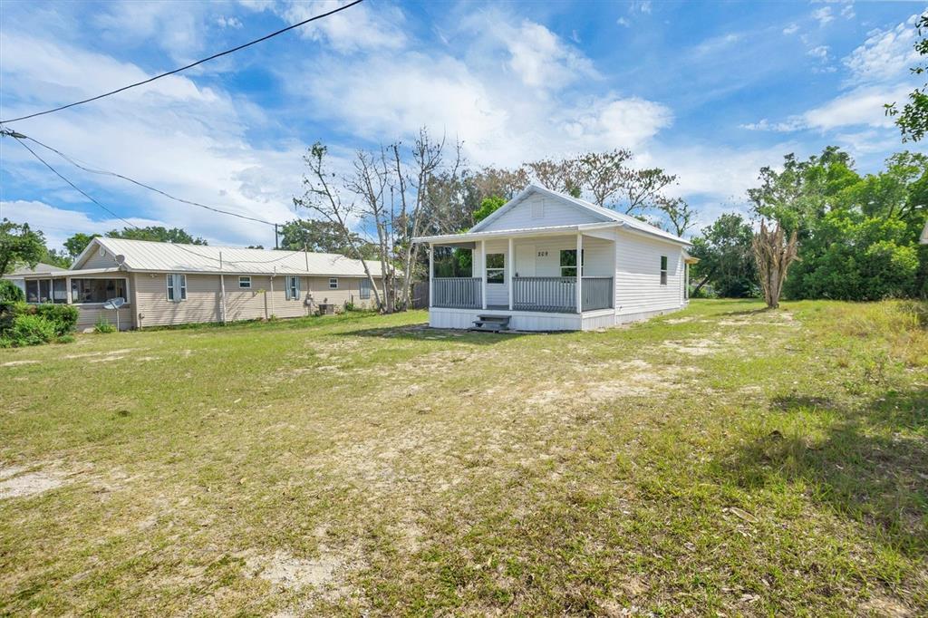 A white house with a front porch sits on a large, grassy lot — 209 PINEY AVENUE, LAKE WALES, FL