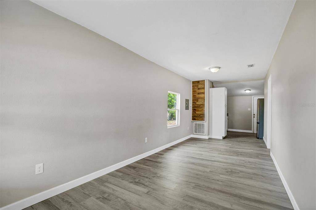 An interior view of a room with light gray walls, wood-look flooring, and a window — 209 PINEY AVENUE, LAKE WALES, FL