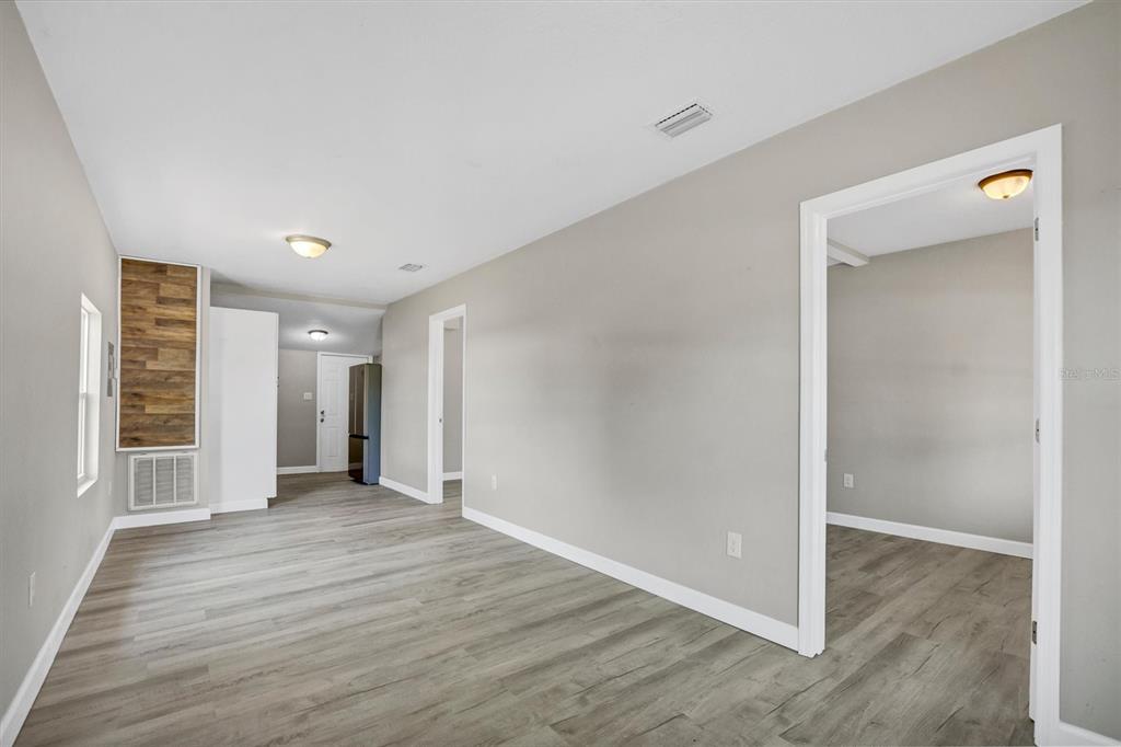 A room with light gray walls, wood-look flooring, and a wood-paneled accent wall — 209 PINEY AVENUE, LAKE WALES, FL
