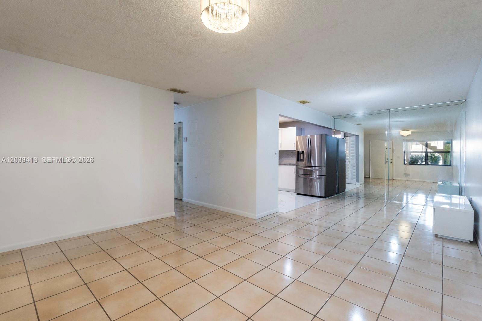 A tiled dining area features a mirrored wall, a stainless steel refrigerator, and white cabinetry — 12940 SW 64th Ln # 3, Miami FL 33183, MIAMI, FL