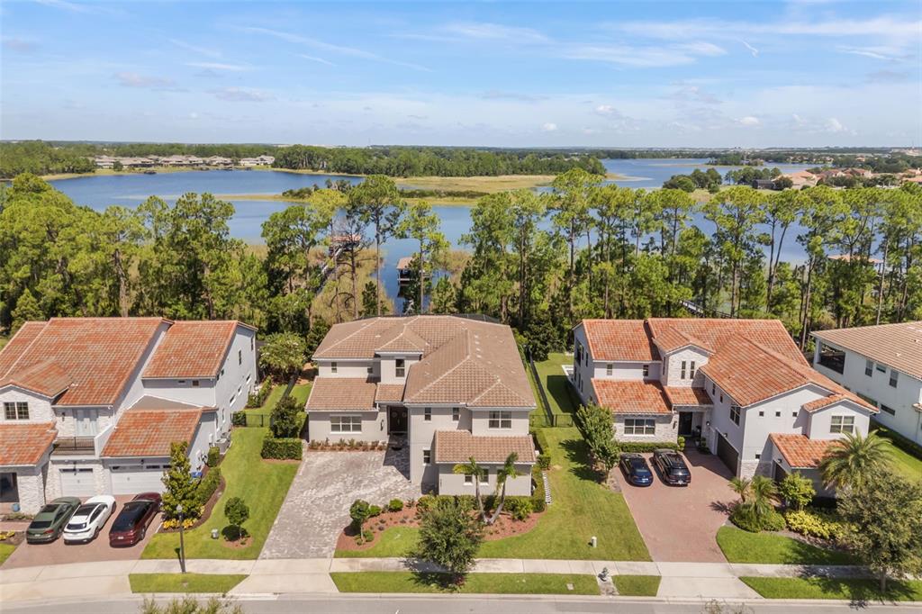 An aerial view shows three suburban houses with tile roofs near a large lake — 9056 MORGANA COURT, WINTER GARDEN, FL
