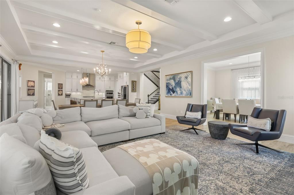 A spacious open-concept living room features a large sectional sofa, two armchairs, and coffered ceilings — 9056 MORGANA COURT, WINTER GARDEN, FL
