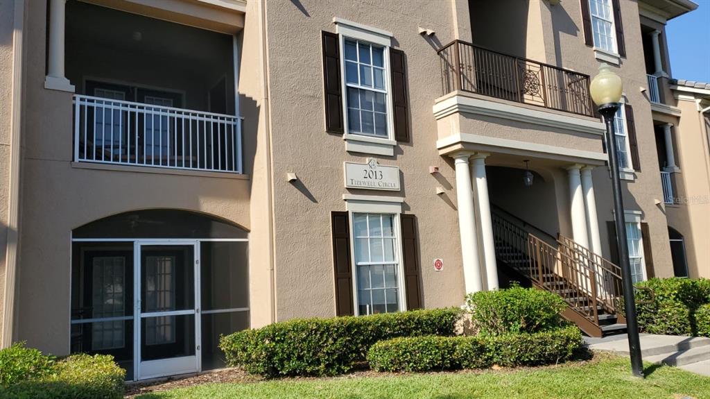 Exterior view of a multi-story apartment building with a screened patio and outdoor staircase — 2013 TIZEWELL CIRCLE UNIT 1403, ORLANDO, FL