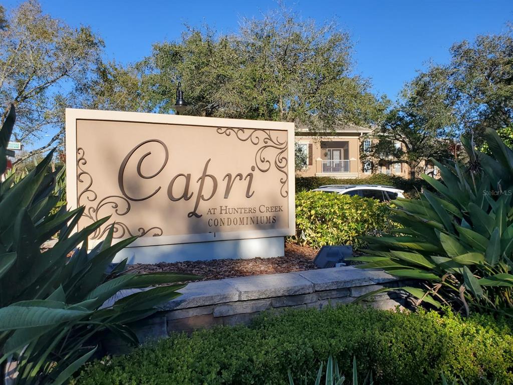 A sign for Capri at Hunters Creek Condominiums stands in front of a residential building — 2013 TIZEWELL CIRCLE UNIT 1403, ORLANDO, FL