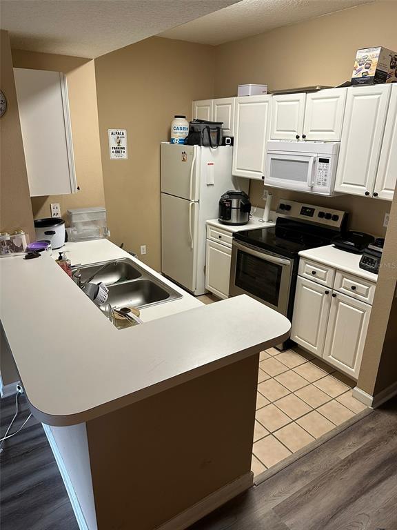 A kitchen features white cabinets, a double sink, a white refrigerator, and a black stove — 2013 TIZEWELL CIRCLE UNIT 1403, ORLANDO, FL