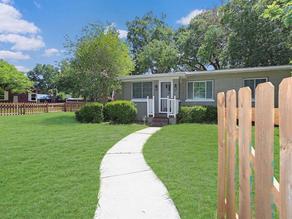 A concrete walkway leads to the front entrance of a single-story house with gray siding — 2541 S PALMETTO AVENUE, SANFORD, FL