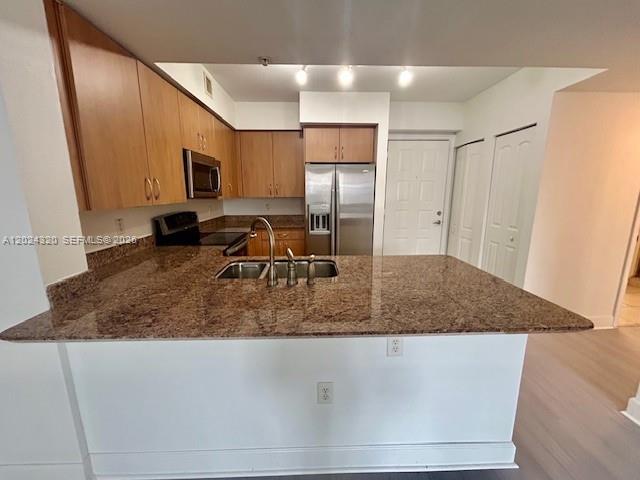 A kitchen features wood cabinets, granite countertops, a stainless steel refrigerator, and a breakfast bar — 1830 Radius Dr # 603, Hollywood FL 33020, HOLLYWOOD, FL