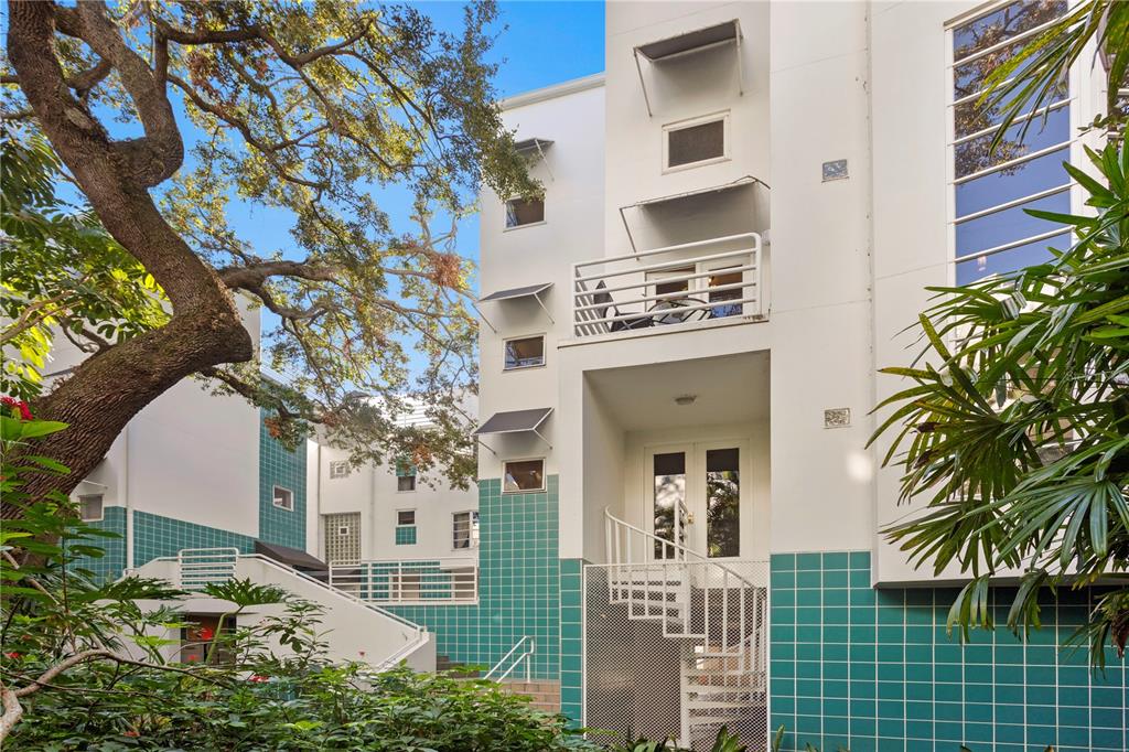 Exterior view of a multi-story white building with teal tiled walls and a spiral staircase — 4950 BAYSHORE BOULEVARD UNIT 13C, TAMPA, FL