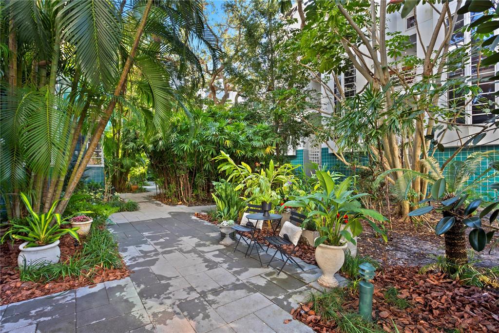 A paved patio area with a small bistro set surrounded by lush tropical landscaping — 4950 BAYSHORE BOULEVARD UNIT 13C, TAMPA, FL