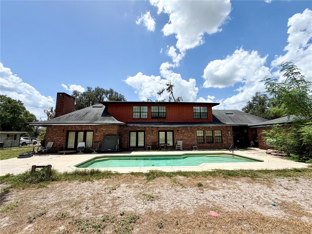 A two-story brick house with a swimming pool and a large backyard under a blue sky — 1880 HERMOSA AVENUE, BARTOW, FL