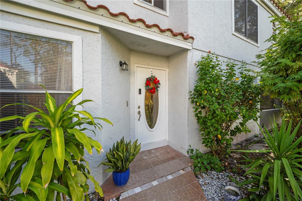 The exterior entrance of a white stucco house features a front door with a wreath — 2649 ALBION AVENUE, ORLANDO, FL