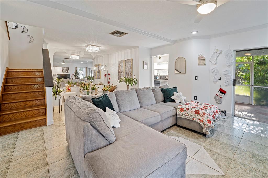 A living room features a large gray sectional sofa, tiled floors, and a wooden staircase — 2649 ALBION AVENUE, ORLANDO, FL