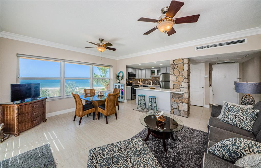 An open-concept living and dining area features tile floors, a stone pillar, and ocean views — 880 MANDALAY AVENUE UNIT S202, CLEARWATER, FL