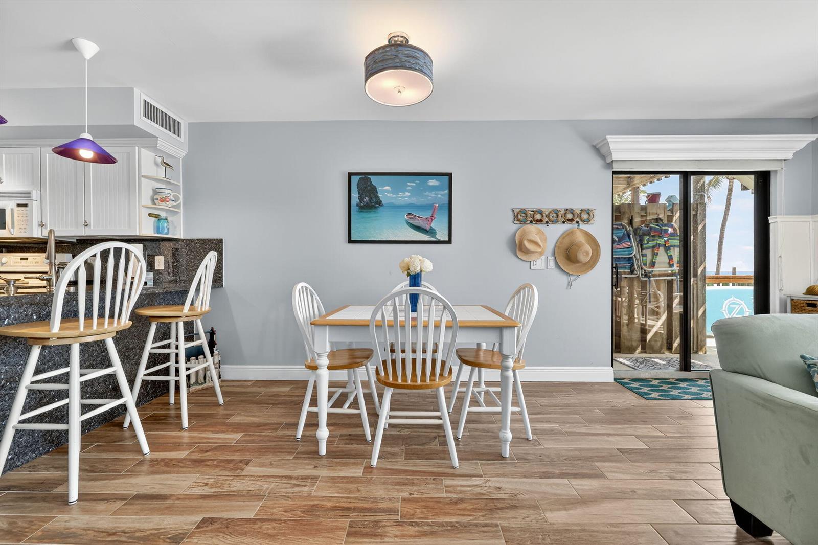 A dining area with a wooden table, white chairs, and a kitchen counter with stools — 2355 NE Ocean Boulevard # 17a, Stuart FL 34996, STUART, FL