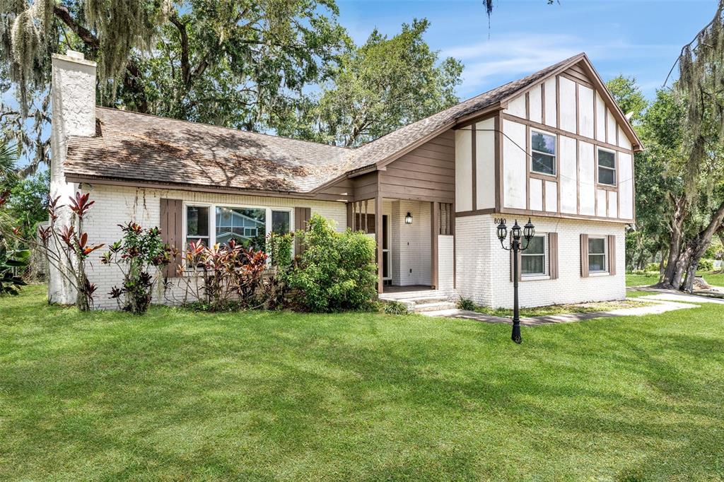 A two-story house with white brick, brown trim, and a large front lawn — 8020 TIERRA VERDE DRIVE, TAMPA, FL