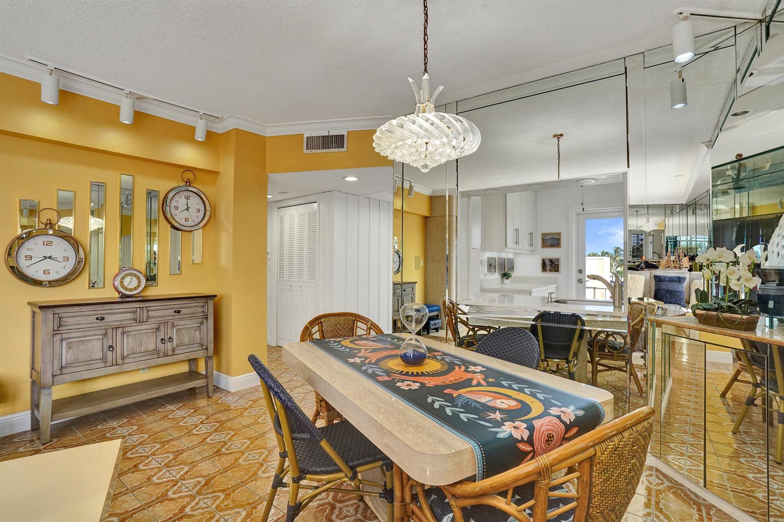 A dining room with yellow walls, a stone table, rattan chairs, and mirrored wall panels — 1481 S Ocean Boulevard # 412, Pompano Beach FL 33062, POMPANO BEACH, FL