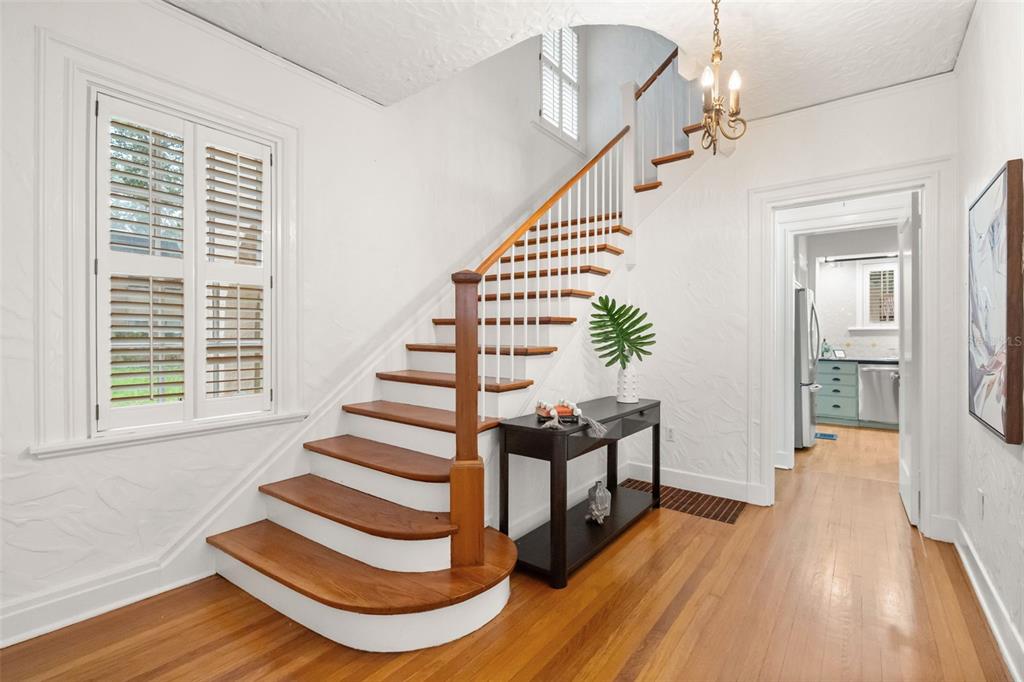A wooden staircase with white risers stands in a foyer with hardwood floors and shutters — 732 EDGEWATER DRIVE, ORLANDO, FL