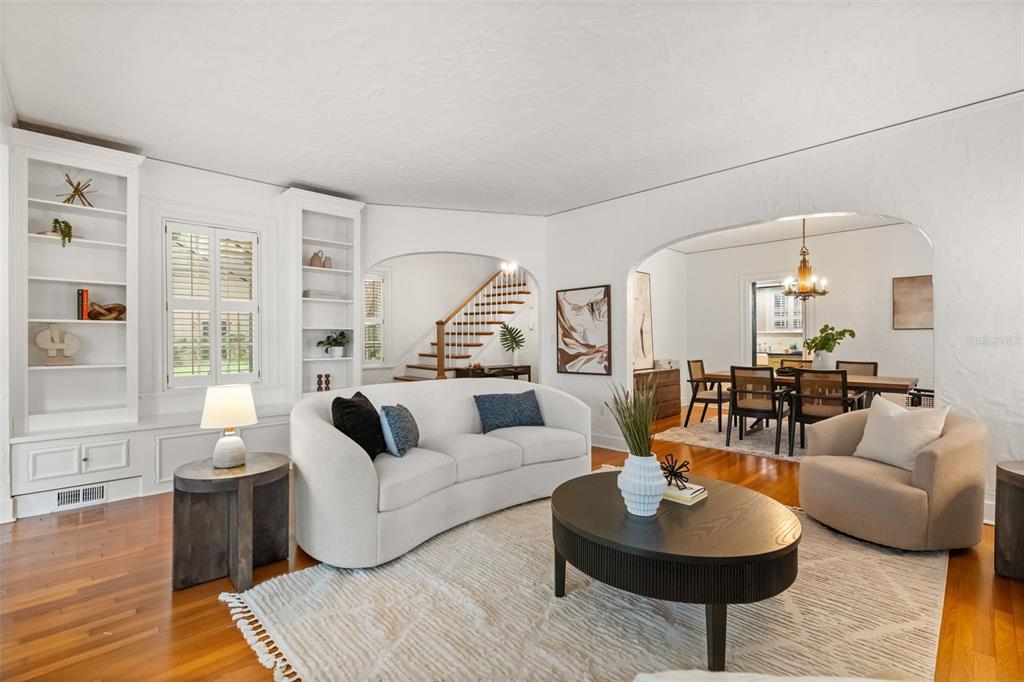 A living room with hardwood floors, a curved sofa, built-in shelving, and an arched entryway — 732 EDGEWATER DRIVE, ORLANDO, FL