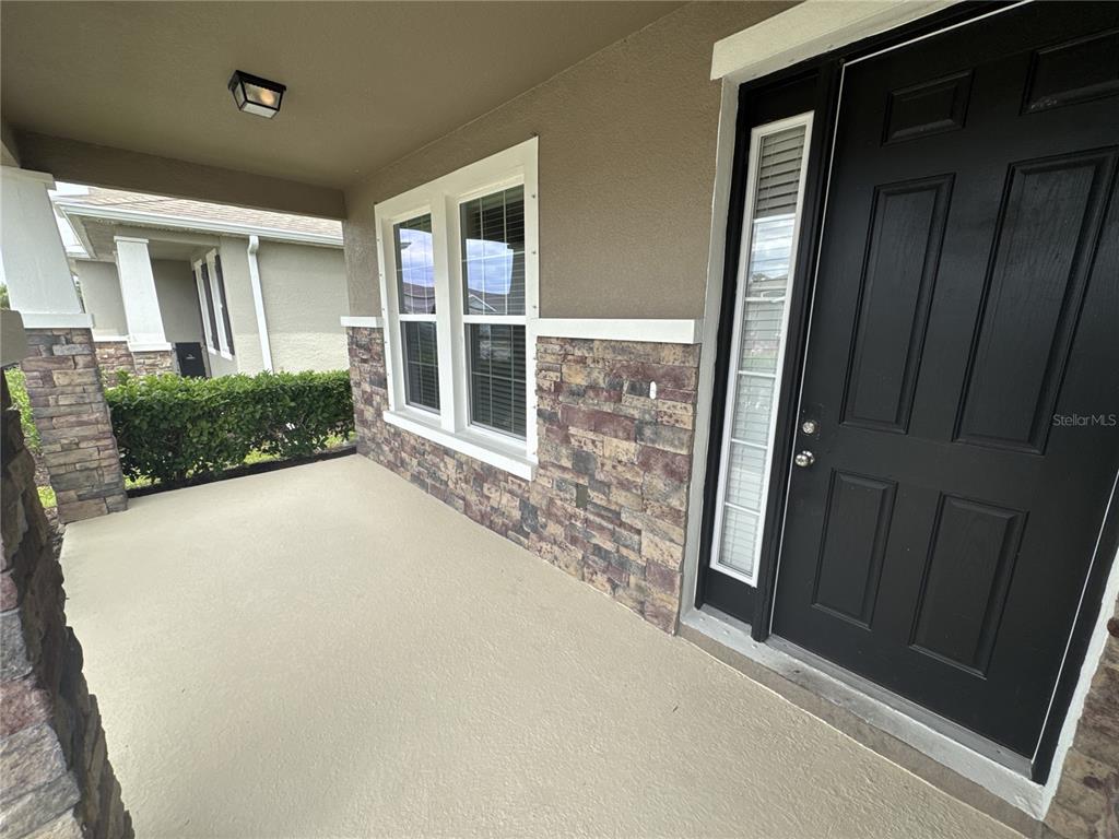 A covered front porch features a black door, stone veneer siding, and two windows — 6356 MIGHTY EAGLE WAY, SARASOTA, FL
