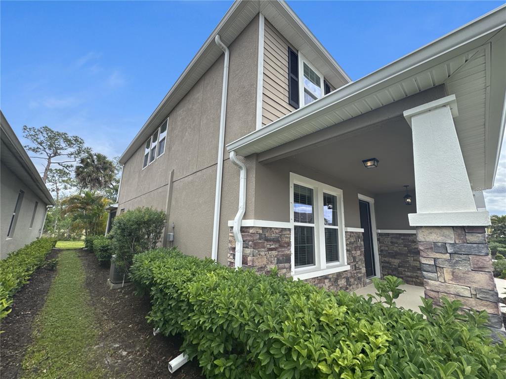 The exterior of a two-story house features tan stucco, stone veneer, and a covered porch — 6356 MIGHTY EAGLE WAY, SARASOTA, FL
