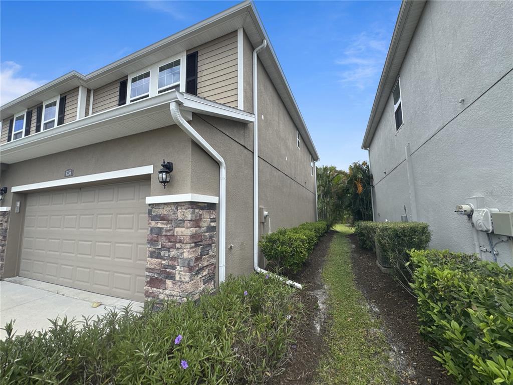 A side view of a two-story house with a garage and a narrow grassy walkway — 6356 MIGHTY EAGLE WAY, SARASOTA, FL