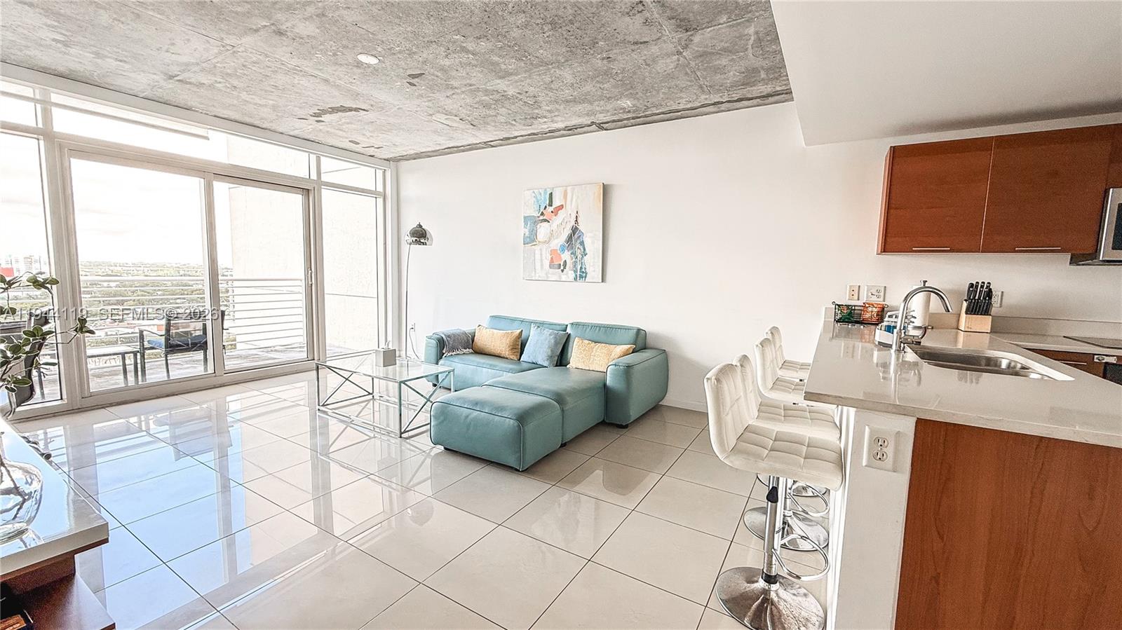 A modern living room and kitchen area features a concrete ceiling and tiled floors — 3250 NE 1st Ave # 1110, Miami FL 33137, MIAMI, FL