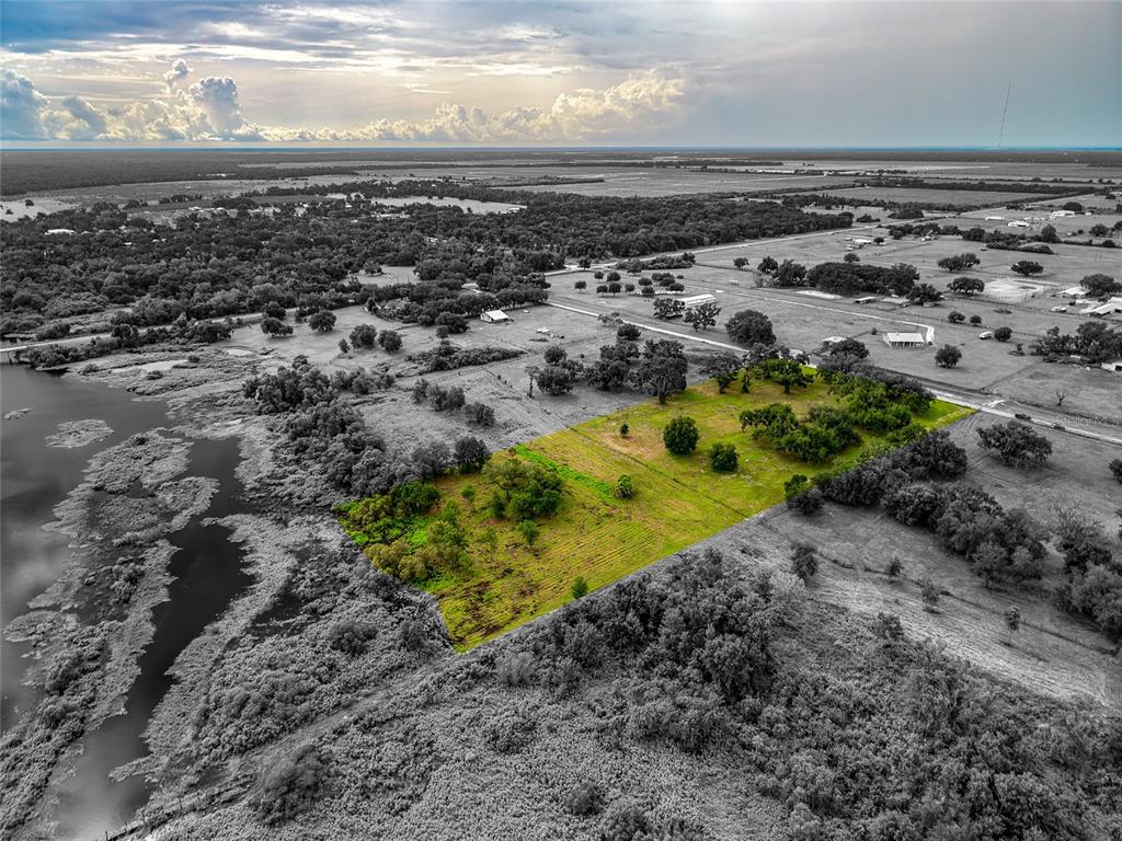 An aerial view shows a rectangular plot of green land surrounded by trees and water — 26207 39TH PLACE E, MYAKKA CITY, FL