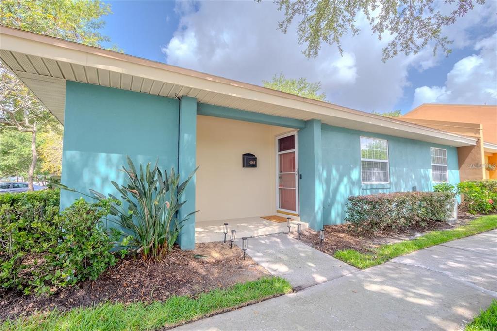 The exterior of a teal-colored house features a covered entryway, a walkway, and landscaping — 4768 TANGERINE AVENUE UNIT 4768, WINTER PARK, FL