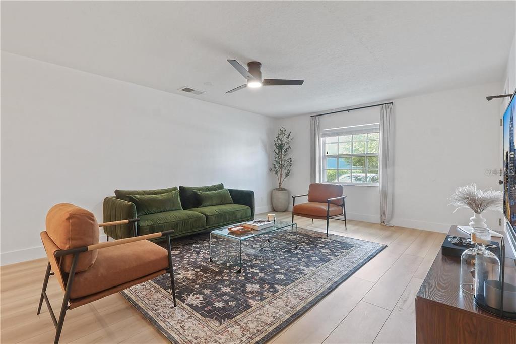 A living room features a green sofa, two brown chairs, a glass table, and rug — 4768 TANGERINE AVENUE UNIT 4768, WINTER PARK, FL