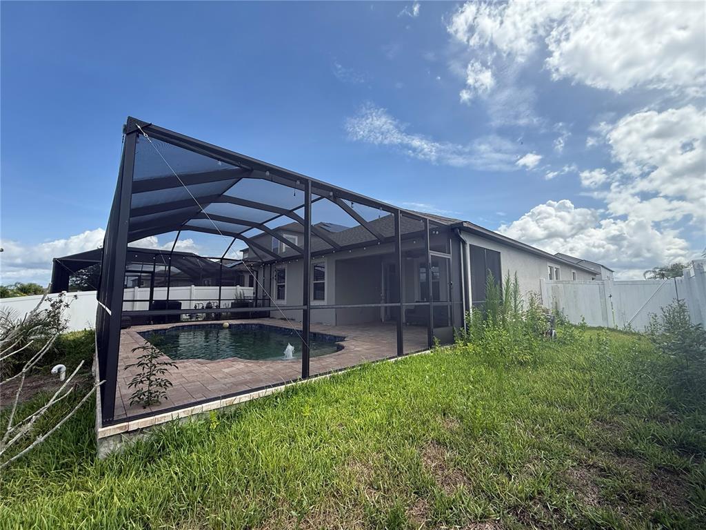 A backyard view of a house with a screened-in pool and patio area — 11865 SUNBURST MARBLE ROAD, RIVERVIEW, FL