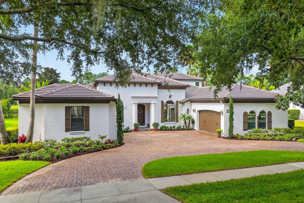 A white stucco house with a brown tile roof and a brick paver driveway — 9620 SAN FERNANDO COURT, HOWEY IN THE HILLS, FL