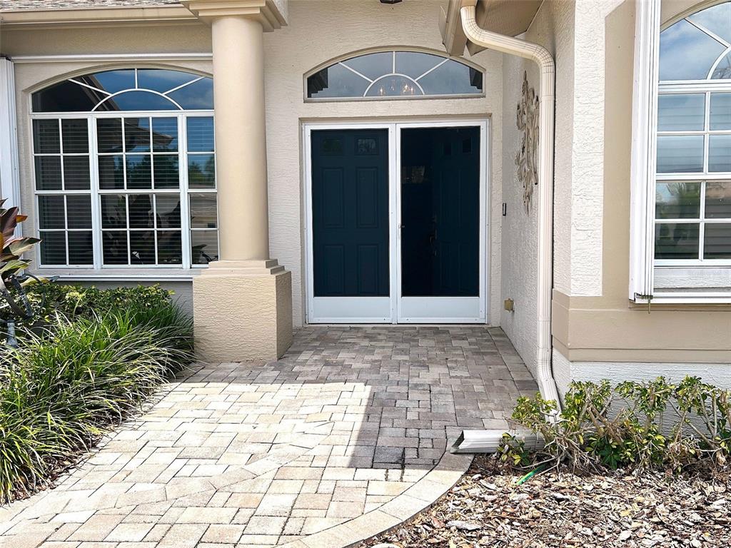 The front entrance features a paved walkway leading to double doors with a transom window — 18530 WATER LILY LANE, HUDSON, FL