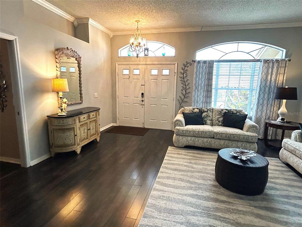 A living room features dark wood floors, a double front door, and a patterned sofa — 18530 WATER LILY LANE, HUDSON, FL