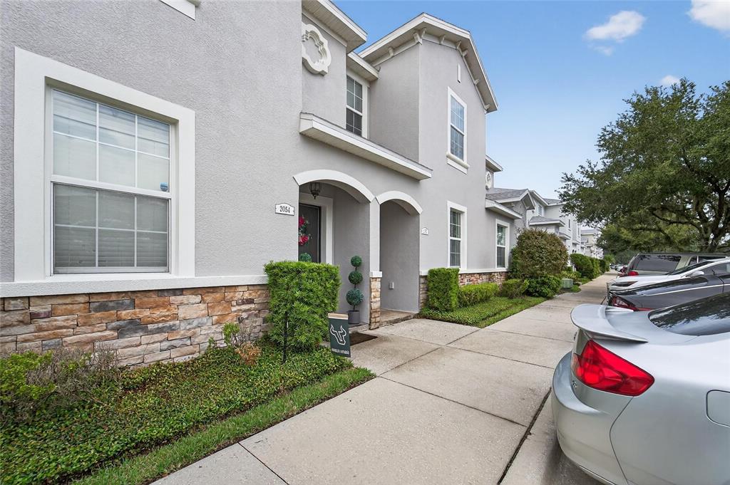 A two-story gray stucco townhouse with stone veneer accents and a concrete walkway — 2052 GREENWOOD VALLEY DRIVE, PLANT CITY, FL