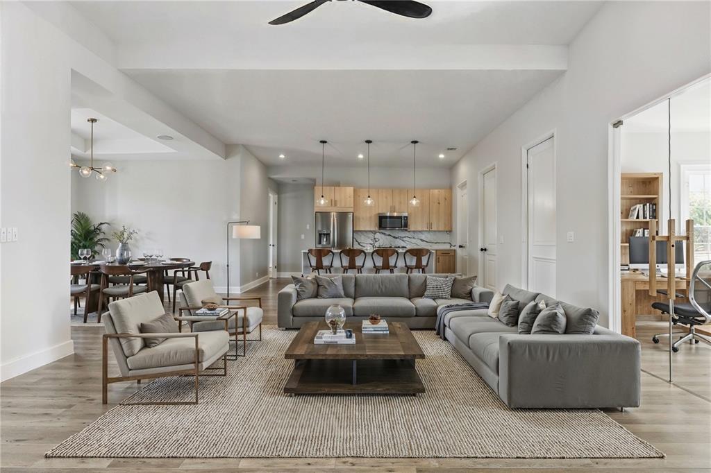 An open-concept living room features a grey sectional, two armchairs, and a kitchen with wood cabinets — 14192 FORT MYERS AVENUE, PORT CHARLOTTE, FL