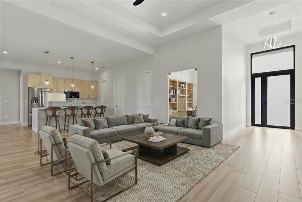 A modern open-concept living room features light wood floors, a gray sectional, and a kitchen — 14192 FORT MYERS AVENUE, PORT CHARLOTTE, FL
