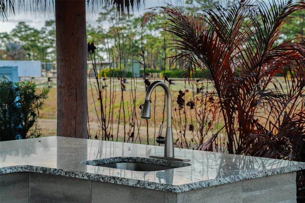An outdoor kitchen island features a granite countertop, a stainless steel sink, and a faucet — HIGHWAY 630 E UNIT 15, LAKE WALES, FL