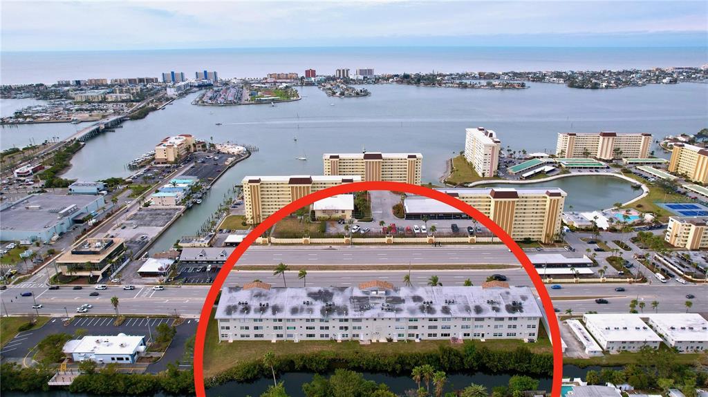 An aerial view shows a multi-story residential building circled in red near a coastal waterway — 4455 DUHME ROAD UNIT 203, ST PETERSBURG, FL