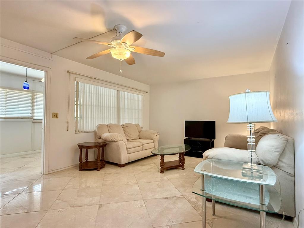 A living room features light-colored tile floors, two sofas, a coffee table, and a ceiling fan — 4455 DUHME ROAD UNIT 203, ST PETERSBURG, FL