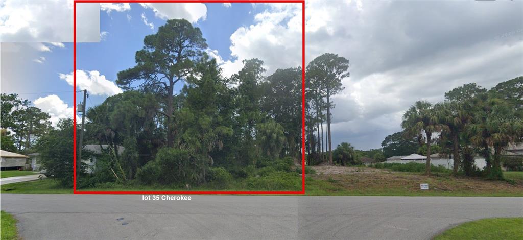 A vacant, wooded residential lot is bordered by a paved road and neighboring houses — CHEROKEE STREET, NORTH PORT, FL