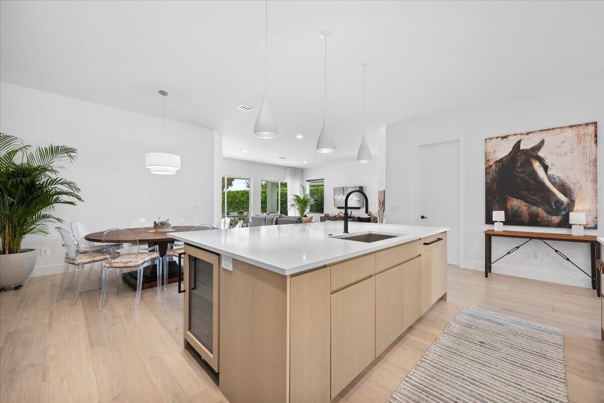 A modern kitchen features a light wood island, white countertops, and a dining area nearby — 2951 Twin Oaks Way, Wellington FL 33414, WELLINGTON, FL