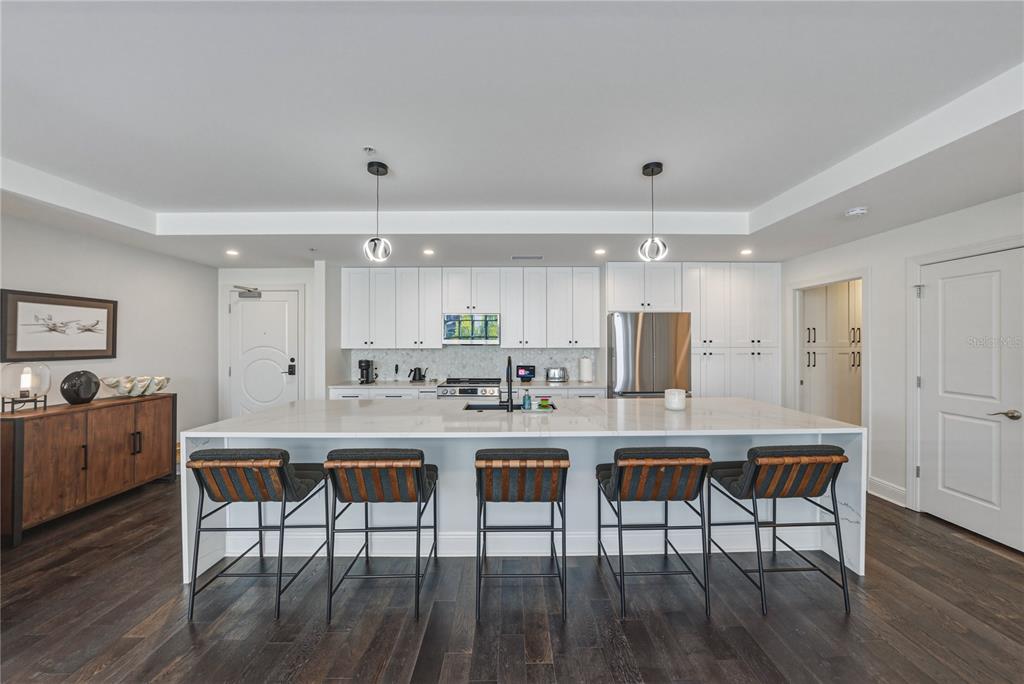 A modern kitchen features a large white quartz island with five stools and white cabinetry — 1227 E MADISON STREET UNIT 504, TAMPA, FL