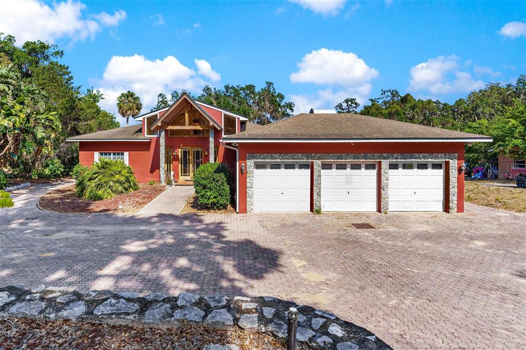 A red house with a three-car garage and a large paved driveway — 2400 N GRIFFIN DRIVE, LEESBURG, FL