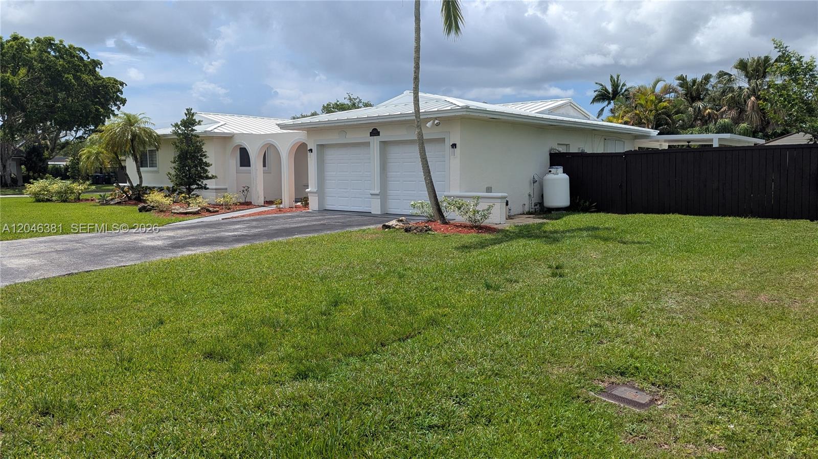 The exterior of a white house features arched entryways, a dark door, and a walkway — 10442 SW 114th St, Miami FL 33176, MIAMI, FL