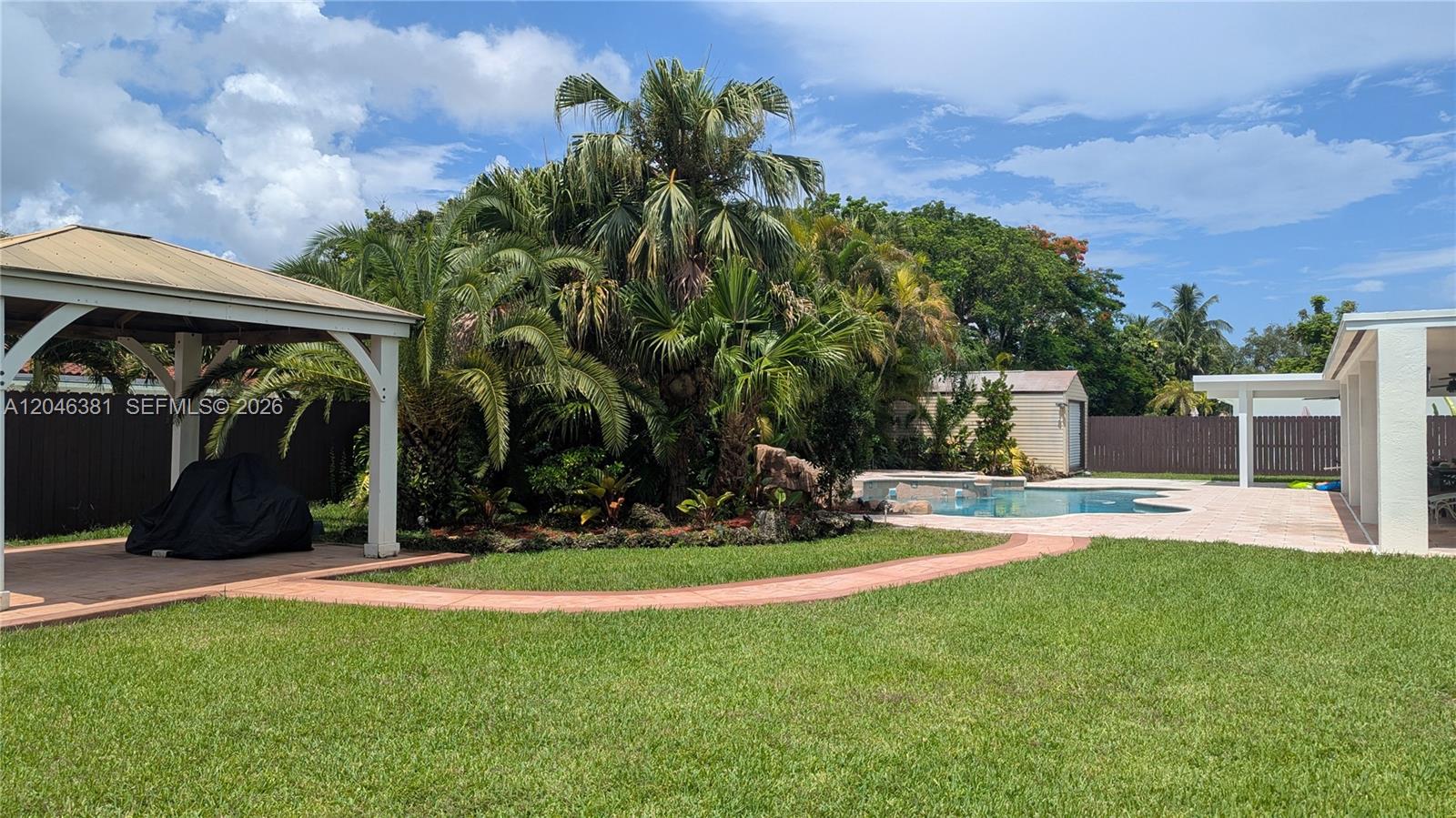 A yellow fire hydrant stands on a grassy lawn in front of a fenced house — 10442 SW 114th St, Miami FL 33176, MIAMI, FL