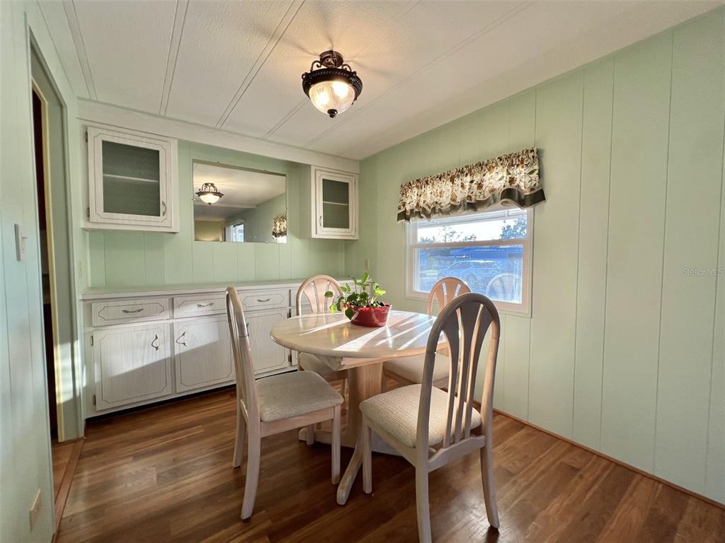 A dining area features light green paneled walls, a round table with chairs, and cabinetry — 169 BOUGAINVILLEA DRIVE, LEESBURG, FL