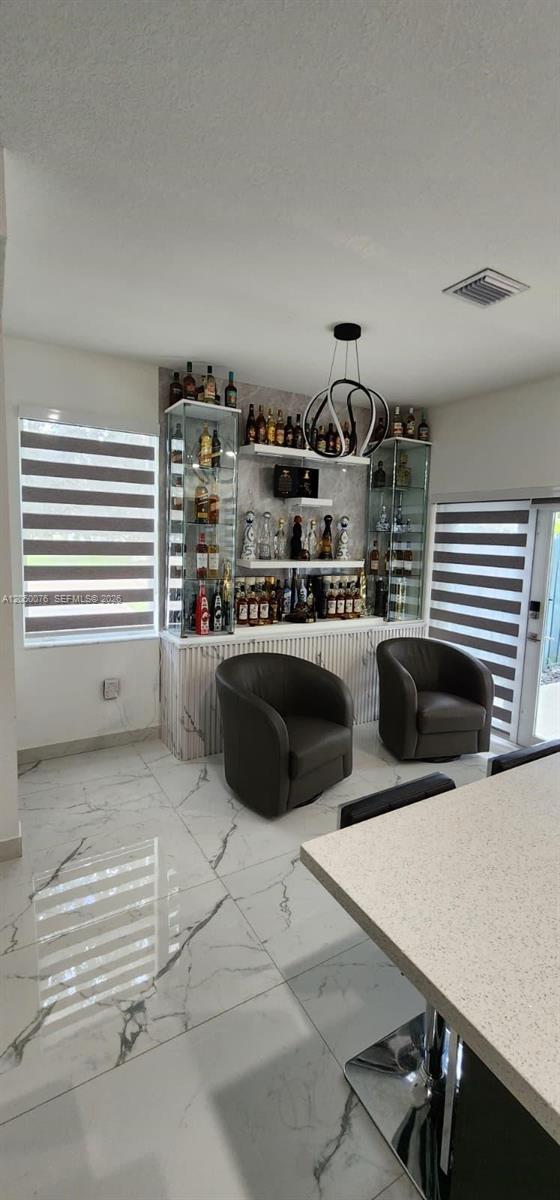 A home bar area features glass display cabinets, shelves, two armchairs, and marble-look tile flooring — 1664 SE 27th Ter, Homestead FL 33035, HOMESTEAD, FL