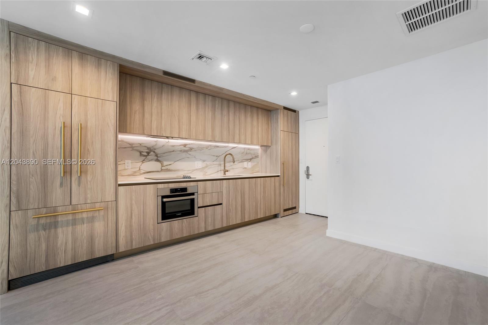 A modern kitchen features light wood cabinetry, marble backsplash, and integrated stainless steel appliances — 77 SE 5th Street # 1708, Miami FL 33131, MIAMI, FL